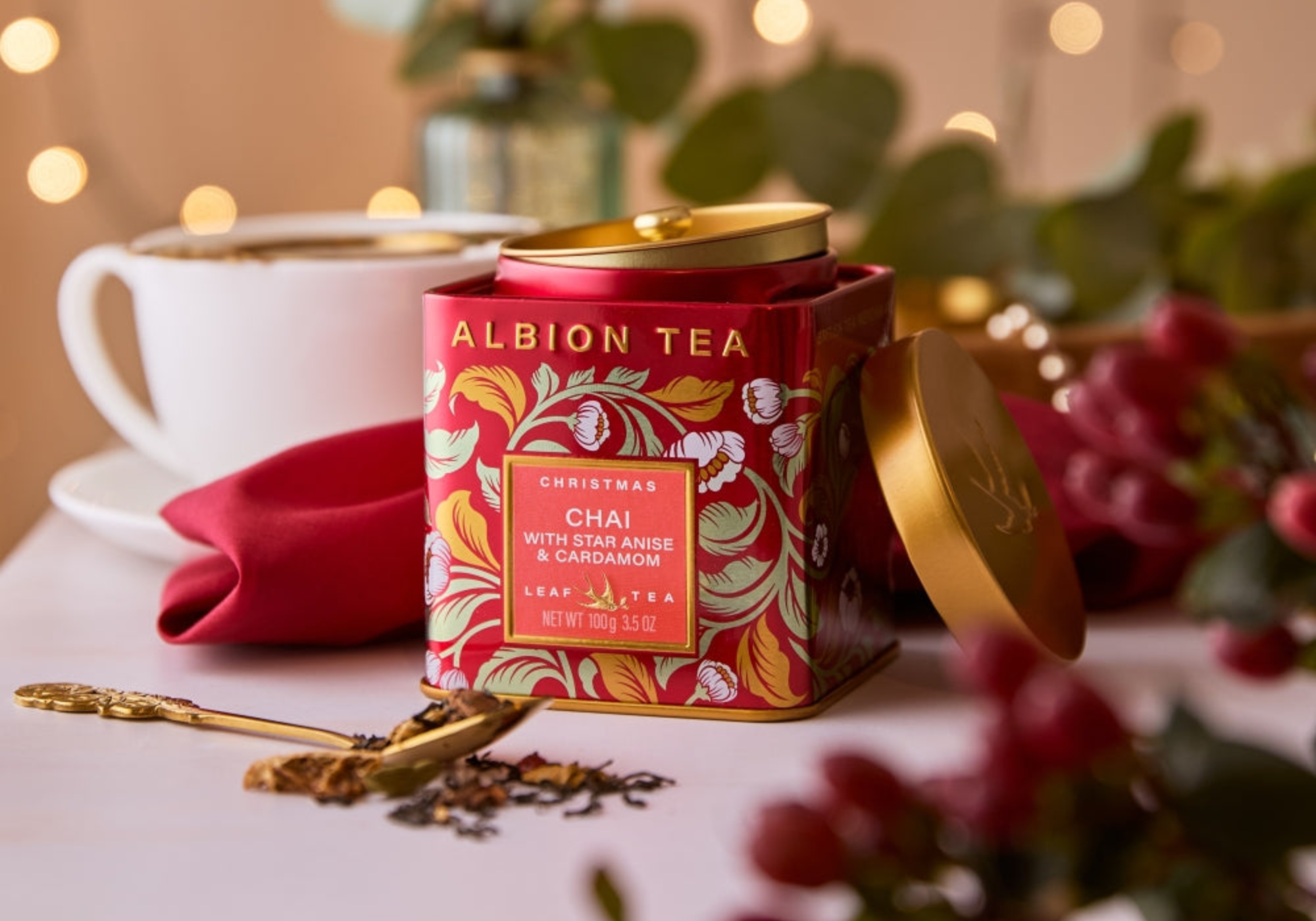 Albion Tea Christmas Chai tea canister with a cup and decorative elements on a table.