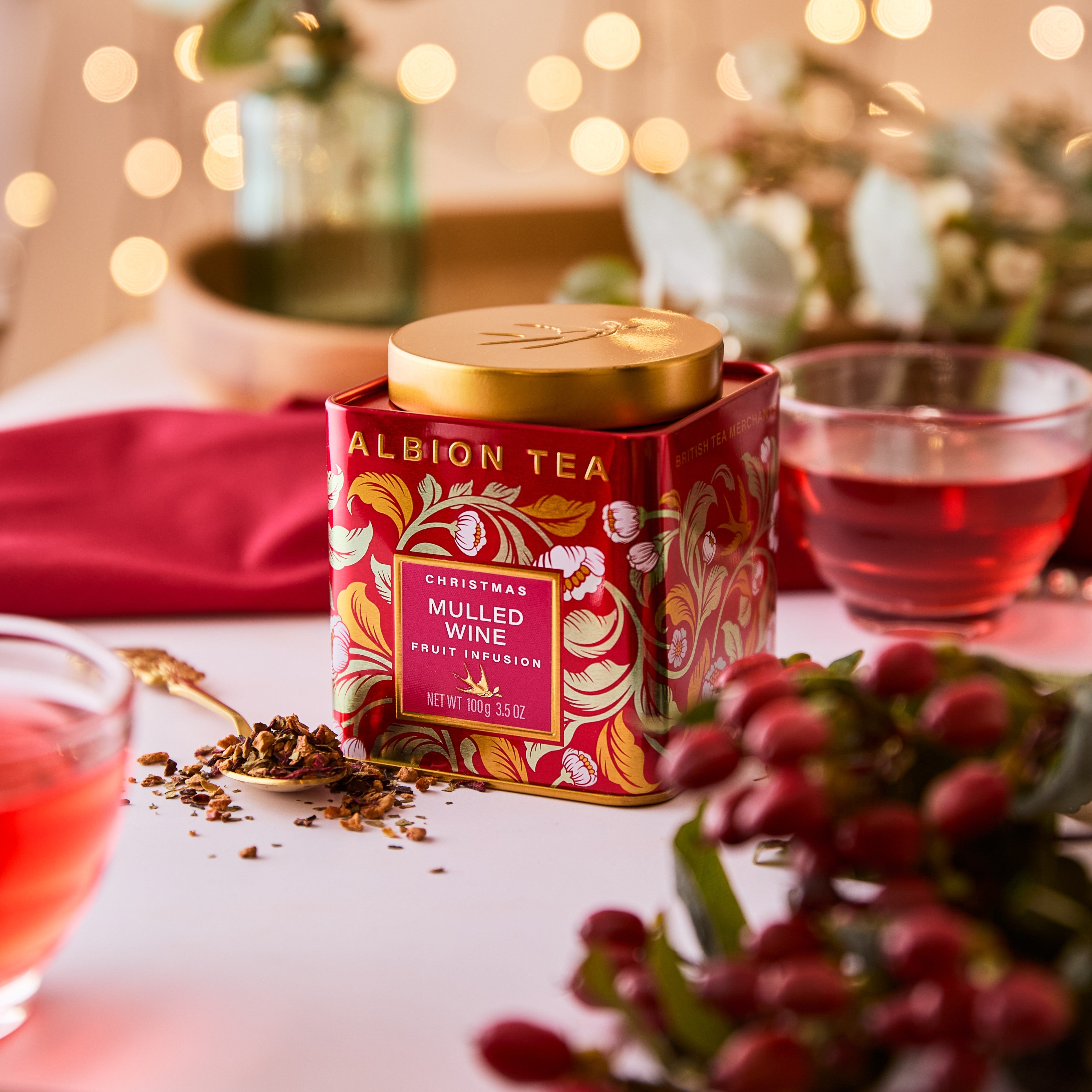 Albion Tea Christmas Mulled Wine tea caddy on a table with red berries and tea leaves.
